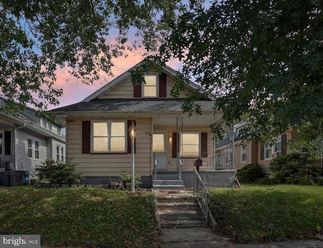 bungalow-style house with a lawn and covered porch