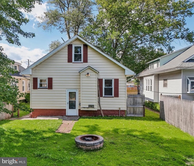 back of property featuring a fire pit and a yard