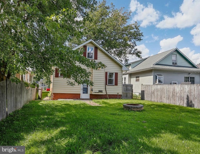 back of property with a fire pit and a lawn