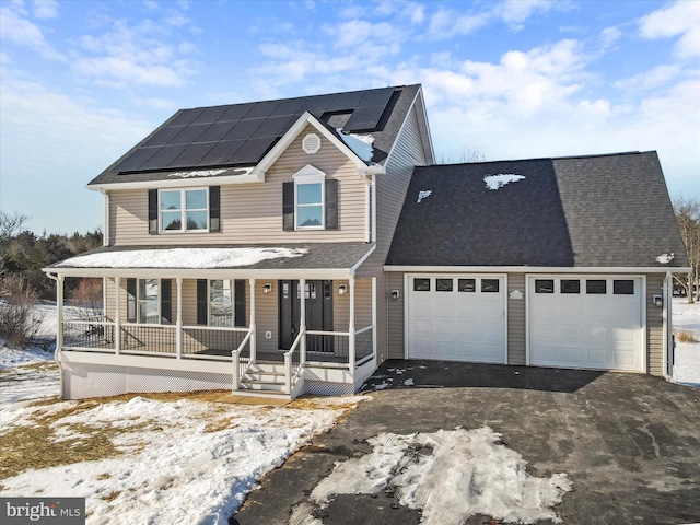 view of front facade featuring a garage, a porch, and solar panels