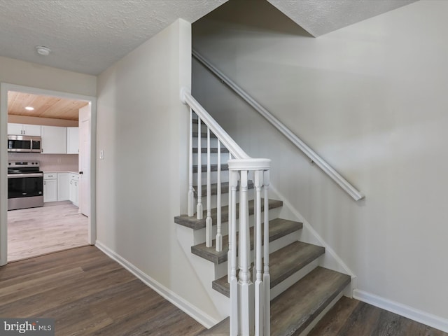 stairs featuring hardwood / wood-style flooring and a textured ceiling