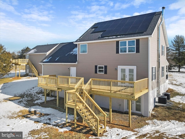 snow covered property featuring central AC, solar panels, and a wooden deck