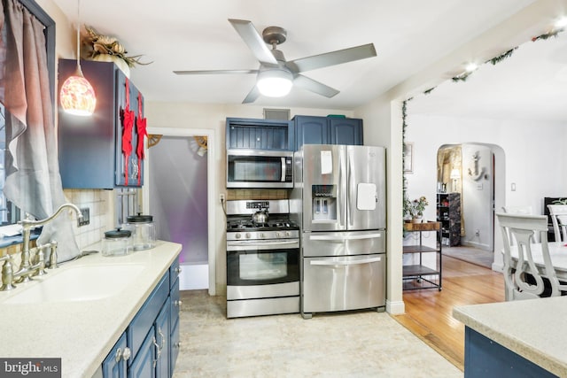 kitchen with decorative backsplash, stainless steel appliances, blue cabinetry, and sink