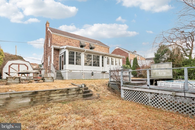 back of house featuring a sunroom, a shed, and a deck