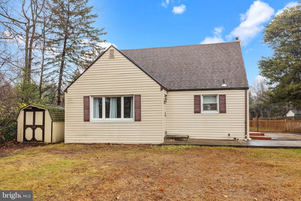 back of property featuring a yard and a storage unit