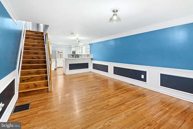 unfurnished living room with light hardwood / wood-style floors and ornamental molding