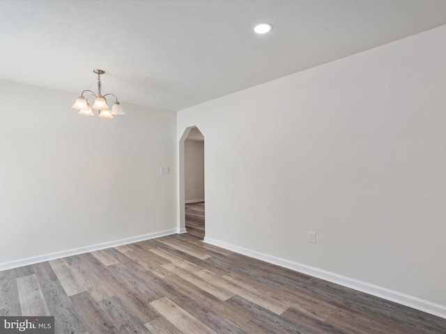 unfurnished room with hardwood / wood-style floors and an inviting chandelier