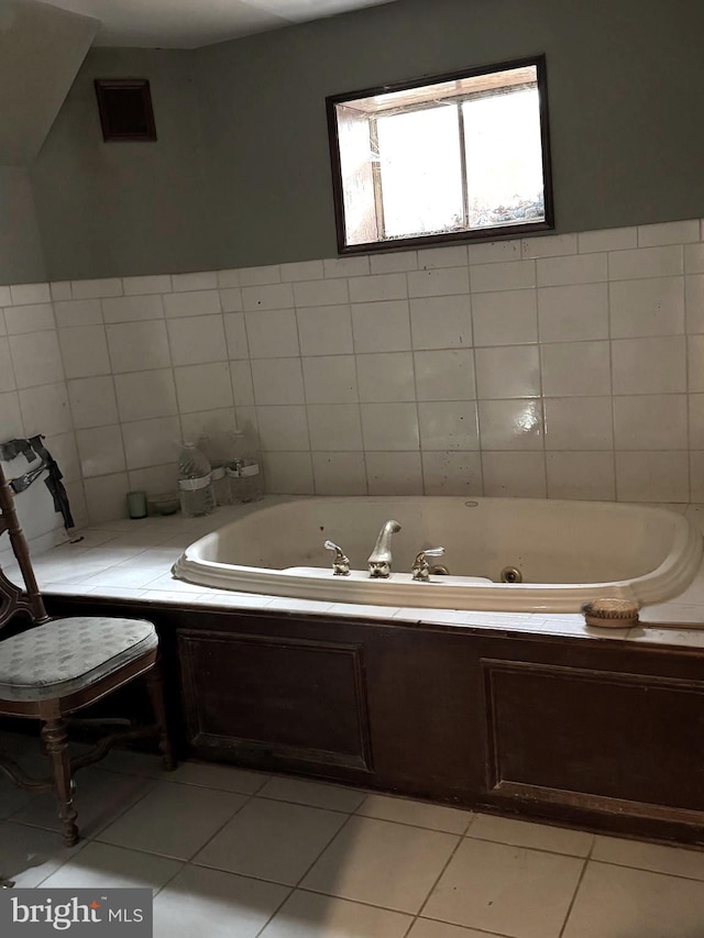 bathroom with a bathing tub, tile patterned flooring, and tile walls