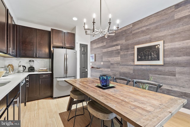 kitchen featuring stainless steel refrigerator, a chandelier, pendant lighting, light hardwood / wood-style floors, and a breakfast bar