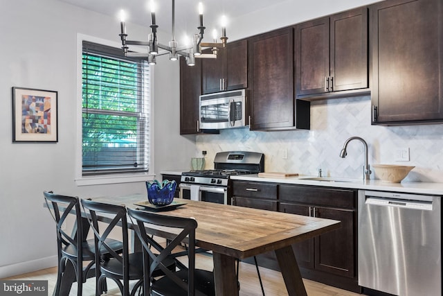 kitchen featuring an inviting chandelier, sink, light hardwood / wood-style flooring, appliances with stainless steel finishes, and dark brown cabinets