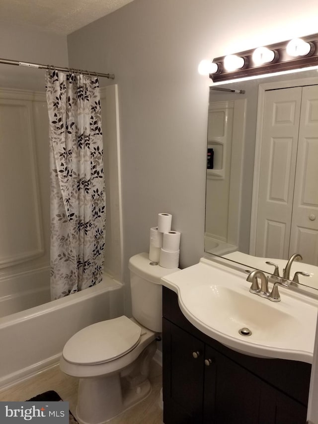 full bathroom featuring hardwood / wood-style floors, a textured ceiling, toilet, shower / bath combo with shower curtain, and vanity