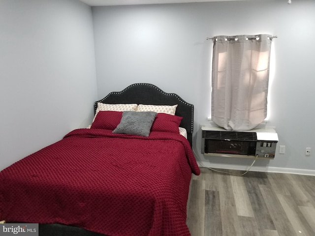 bedroom with heating unit and hardwood / wood-style floors