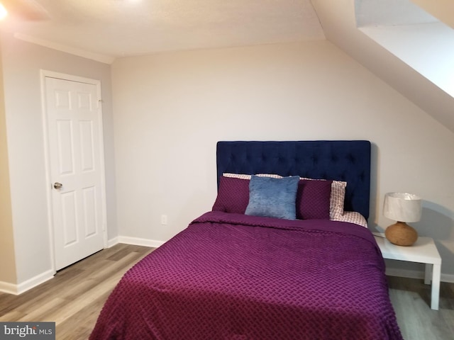 bedroom with hardwood / wood-style floors and lofted ceiling