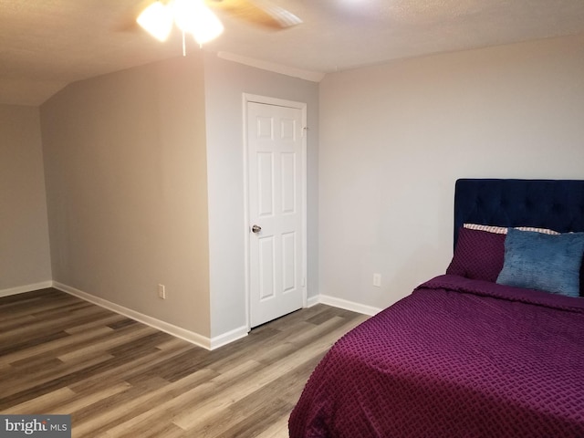 bedroom with ceiling fan, wood-type flooring, and vaulted ceiling