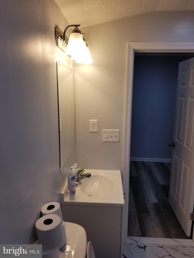 bathroom with hardwood / wood-style floors, vanity, a textured ceiling, and toilet