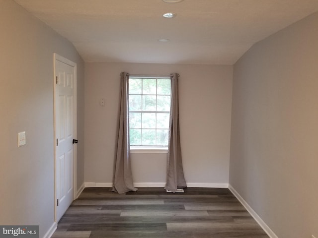 unfurnished room featuring dark hardwood / wood-style floors and lofted ceiling