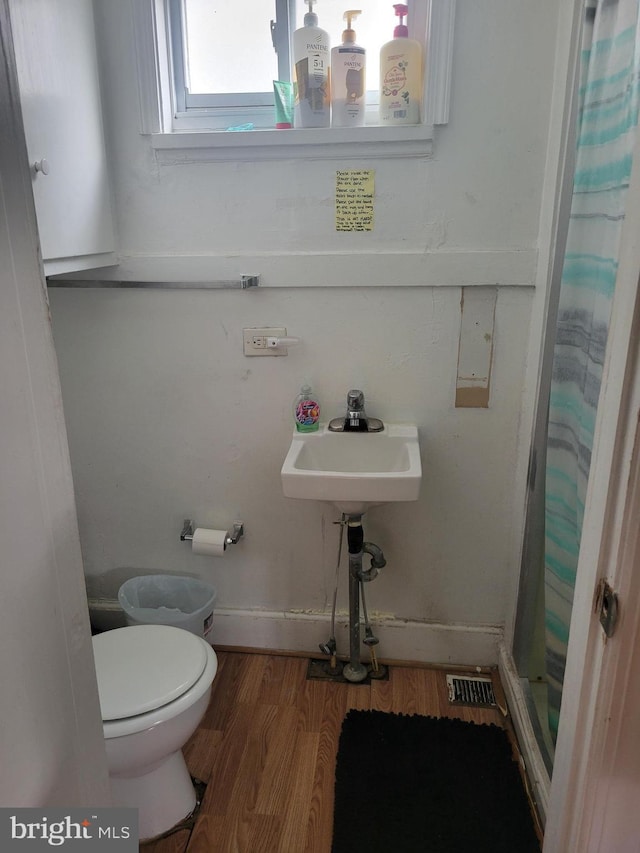 bathroom featuring toilet, a shower with shower curtain, and hardwood / wood-style flooring