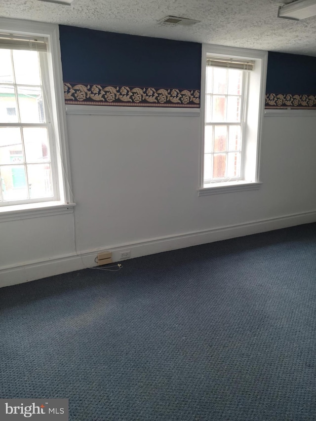 carpeted empty room with a textured ceiling