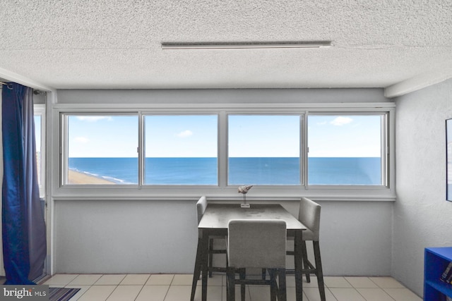 tiled dining space featuring a water view and a textured ceiling