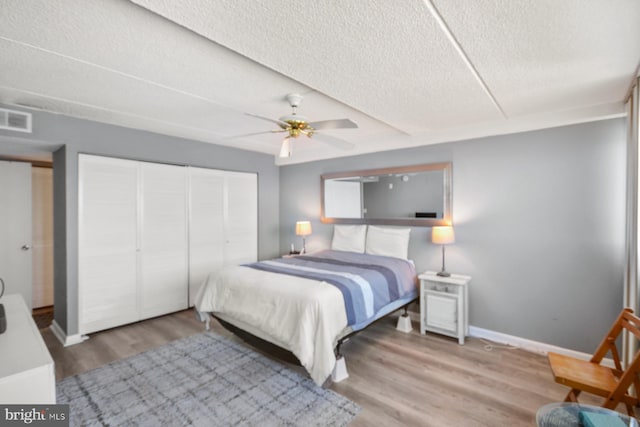 bedroom with wood-type flooring, a textured ceiling, a closet, and ceiling fan