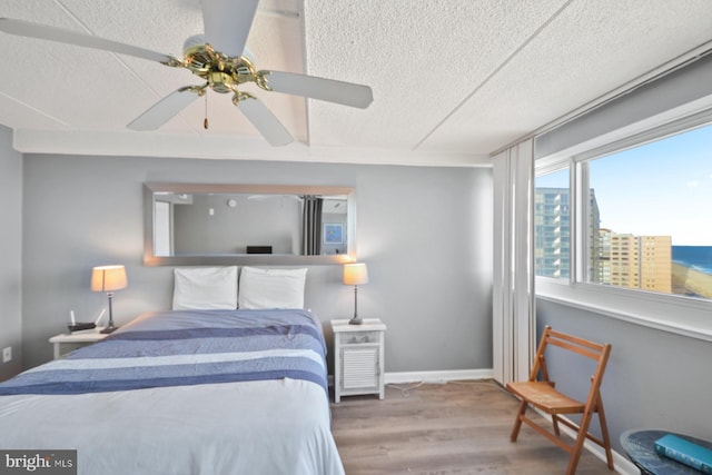 bedroom with hardwood / wood-style floors, a textured ceiling, and ceiling fan