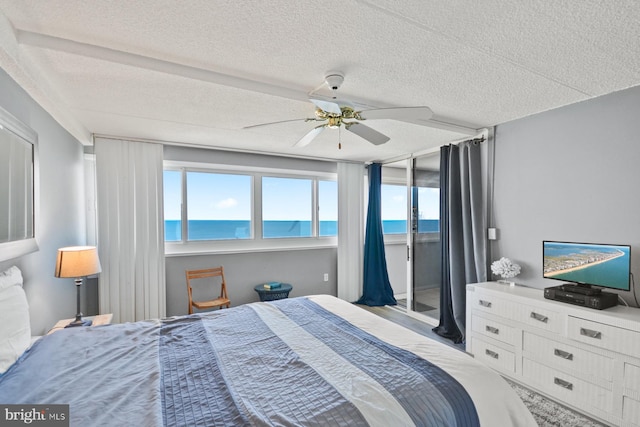 bedroom featuring ceiling fan, access to exterior, and a textured ceiling