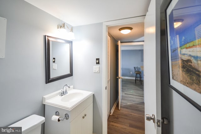 bathroom with hardwood / wood-style flooring, vanity, toilet, and a textured ceiling