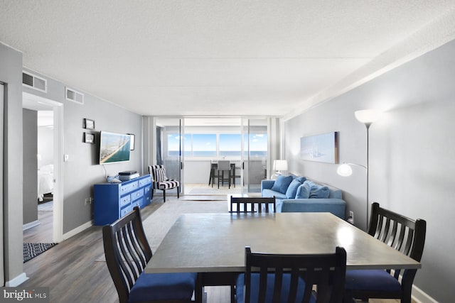 dining space with hardwood / wood-style floors and a textured ceiling