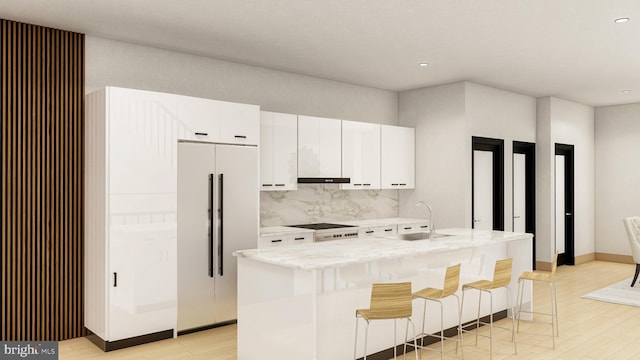 kitchen featuring white cabinetry, an island with sink, sink, decorative backsplash, and built in refrigerator