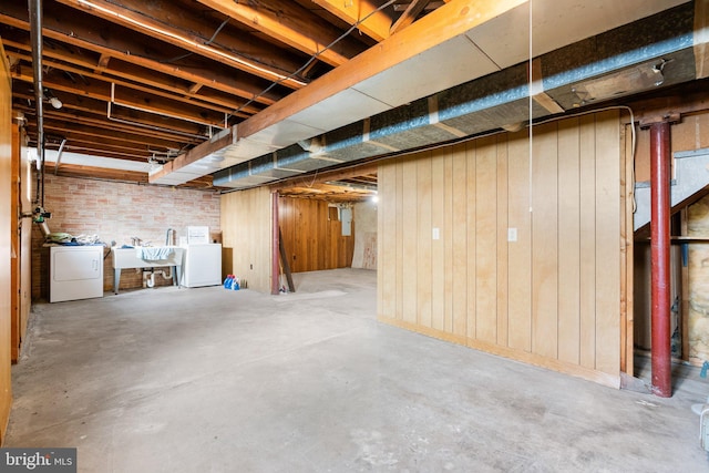 basement with washing machine and dryer, wooden walls, and sink