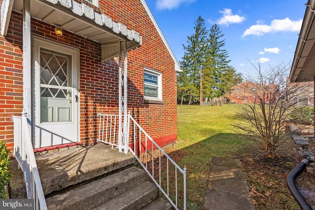 view of exterior entry featuring a lawn