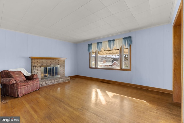 unfurnished living room with a fireplace, hardwood / wood-style flooring, and wooden walls