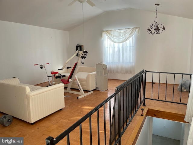 interior space with ceiling fan with notable chandelier, parquet floors, and vaulted ceiling