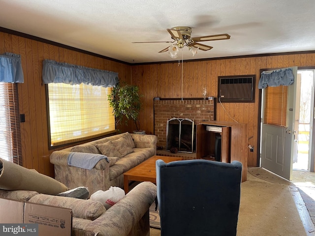 living room featuring ceiling fan, a fireplace, ornamental molding, and wooden walls