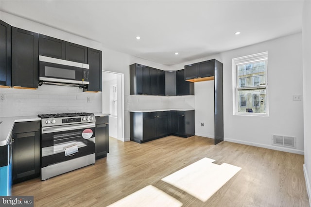 kitchen featuring decorative backsplash, light hardwood / wood-style floors, and appliances with stainless steel finishes