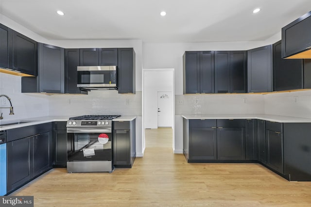 kitchen with tasteful backsplash, sink, stainless steel appliances, and light wood-type flooring