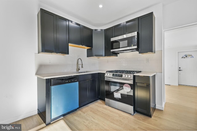 kitchen with backsplash, stainless steel appliances, light hardwood / wood-style floors, and sink