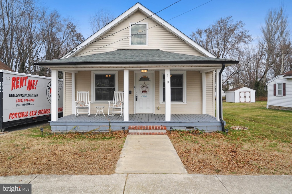 bungalow-style home with covered porch, a shed, and a front lawn