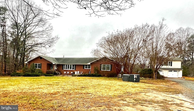 view of front of home featuring a garage, a front lawn, and central air condition unit