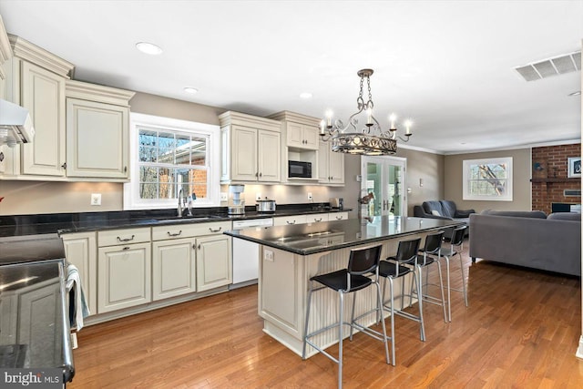 kitchen featuring light hardwood / wood-style floors, pendant lighting, dishwasher, and cream cabinetry