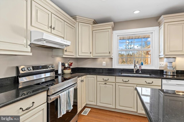 kitchen featuring dishwasher, stainless steel electric range, sink, light wood-type flooring, and cream cabinetry