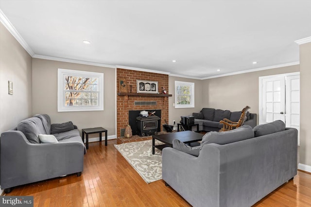 living room featuring wood-type flooring, a wood stove, and ornamental molding