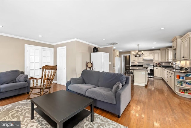 living room with a chandelier, crown molding, light hardwood / wood-style flooring, and sink