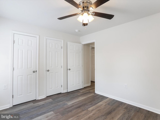 unfurnished bedroom with ceiling fan, two closets, and hardwood / wood-style floors