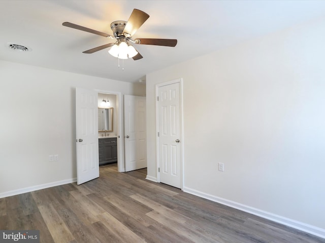 unfurnished bedroom with ceiling fan, dark wood-type flooring, and ensuite bathroom