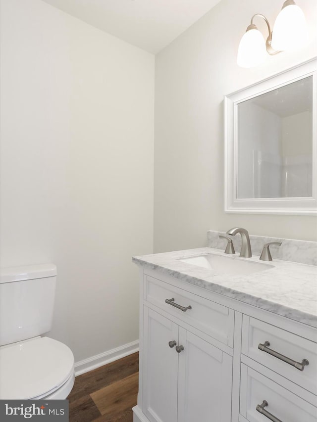 bathroom with hardwood / wood-style flooring, toilet, and vanity