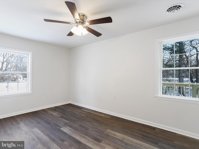 spare room featuring ceiling fan, dark wood-type flooring, and a wealth of natural light