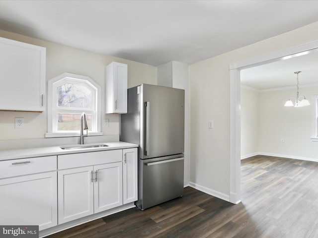 kitchen featuring sink, stainless steel fridge, white cabinetry, a notable chandelier, and dark hardwood / wood-style flooring