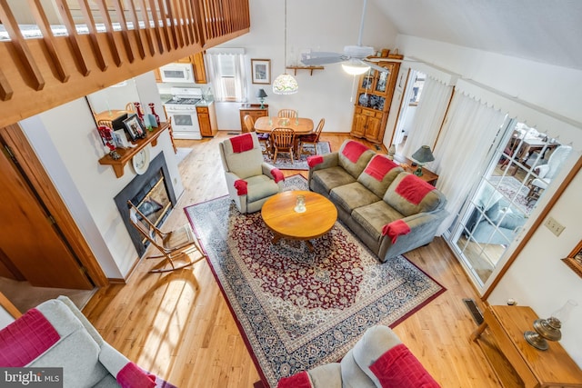 living room with light hardwood / wood-style floors, high vaulted ceiling, and ceiling fan