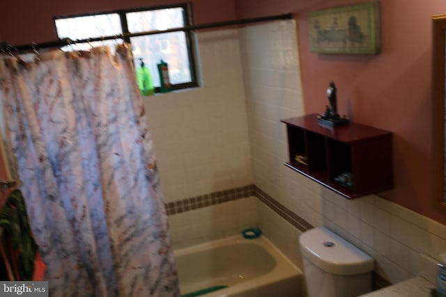 bathroom featuring toilet, tasteful backsplash, and shower / tub combo with curtain